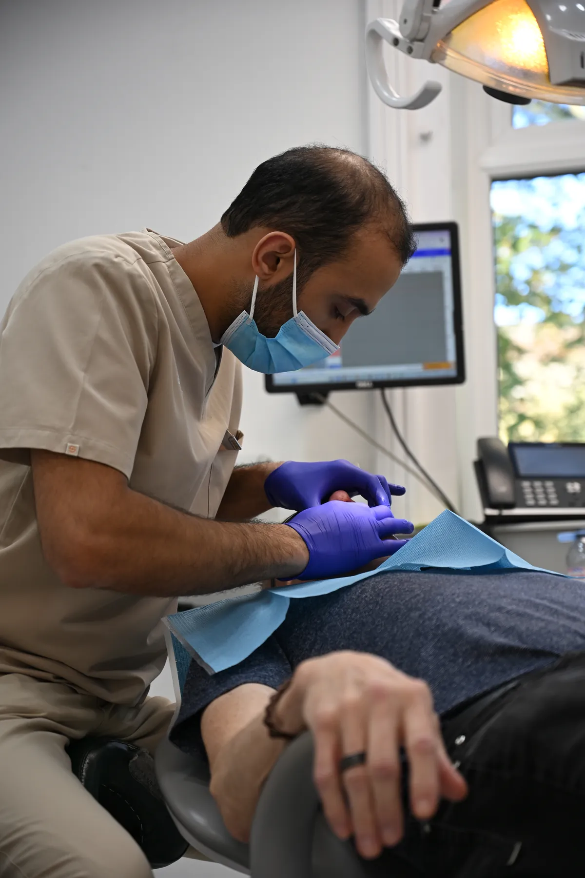 Dr Ibraheem Ijaz adjusting David's new fixed bridge in the dental chair