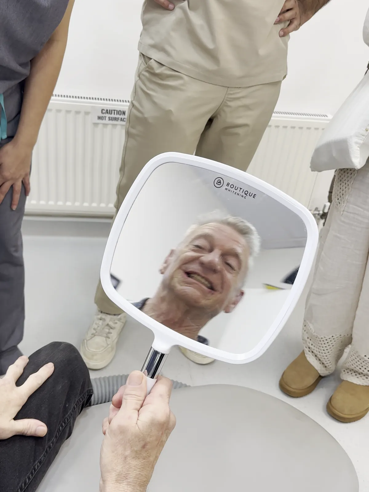 David smiling at his new upper teeth in a hand mirror