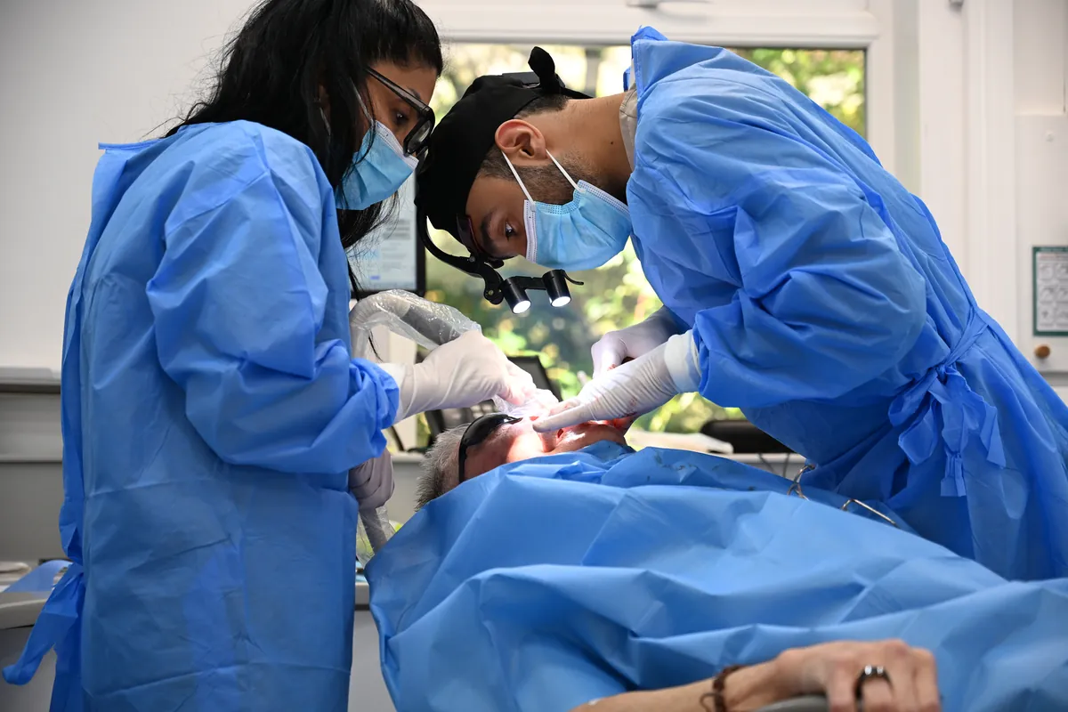 Dr Ibraheem Ijaz and a dental nurse in surgical gowns during David's full arch implant surgery